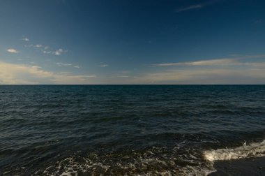 Alacakaranlık dingin okyanus manzarasına sıcak bir parıltı saçarken dalgalar yavaşça kıyıya vurur..