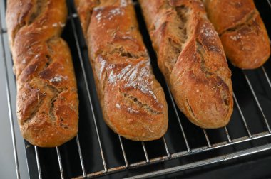 Altın-kahverengi somunlar serinletici bir rafta dinleniyor, kırsal cazibelerini sergiliyorlar ve hoş bir mutfakta davetkar aromalarını sergiliyorlar..