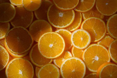 Parlak portakal dilimleri güzel dizilmiş, güneş ışığını yakalıyor ve ferahlık ve neşe hissi uyandırıyor..