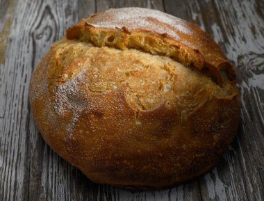 Altın-kahverengi kabuklu ekmek, taze pişmiş nefis bir koku yayarak, eski ahşap yüzeyde yatar..