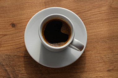 Sıcak, ahşap bir masaya yeni demlenmiş bir fincan kahvenin tadını çıkarın..