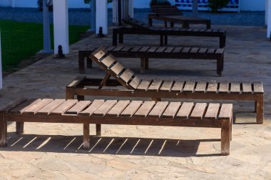 Rahatlatıcı ahşap şezlonglar, sakin bir havuz alanının yanında uzun gölgeler oluşturarak huzurlu anları davet ediyorlar..