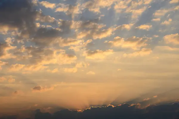 Parlak turuncu ve altın renkleri, sakin bir akşamda bulutların arasından akan güneş ışığı gibi gökyüzünü dolduruyor..