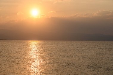 Ilık güneş ışığı sakin sulara yansıyor gün dingin bir sona yaklaşırken, güzel bir altın ufuk yaratıyor..