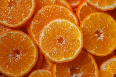 Sulu mandalina dilimleri parlak turuncu renklerini sergiliyor, izleyicileri tatlı ve keskin lezzetlerinin tadını çıkarmaya davet ediyor..