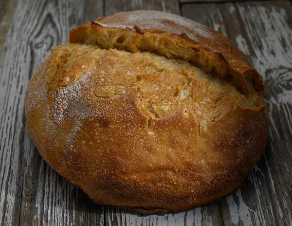 Altın kabuklu ekmek ahşap bir yüzeyde uzanır. Sıcaklığı ve taze pişmiş nefis kokusuyla davet eder..