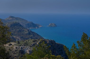 Nefes kesen manzara engebeli kayalıkları ve berrak mavi gökyüzünün altında barış ve güzellik saçan berrak bir denizi yakalar..