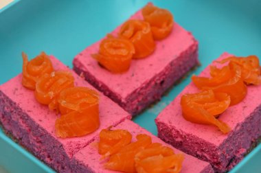 Renkli tatlı kareleri, üzerinde tatlı turuncu bukleler olan pürüzsüz pembe bir tabaka sergiliyor..