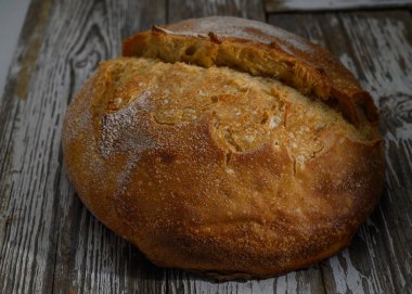 Kabuklu, kahverengi bir somun, ahşap bir yüzeye davetkar bir şekilde oturur ve sıcaklık saçar..