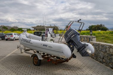 Gaziveren Kıbrıs Rum Kesimi - 01.03.2025 Havada bulutlar belirmeye başlarken, bir otoparktaki bir karavanda duran parlak, şişme bir tekne dinleniyor..