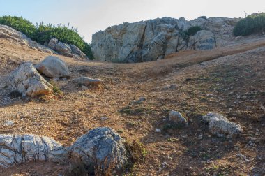 Altın güneş ışığı, kayalık bir araziye açılan dolambaçlı bir yolu aydınlatır. Keşifleri ve maceraları davet eder..