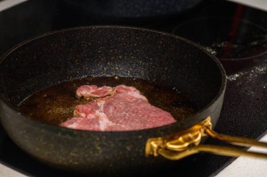 Lezzetli bir parça biftek kızgın yağda kızarıyor, yemek boyunca mutfağı ağız sulandıran aromalarla dolduruyor..