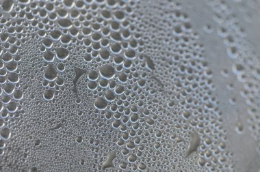 Küçük damlacıklar pürüzsüz bir yüzeye tutunurken parlarlar ve büyüleyici bir su deseni oluştururlar..