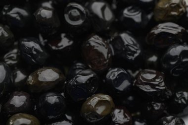 Parlak ve pürüzsüz taşlar yoğun bir şekilde bir araya toplanmış, koyu siyah ve koyu yeşilin çeşitli tonlarını sergiliyorlar. Doku yumuşak bir şekilde parıldıyor, doğal güzelliklerini vurguluyor..