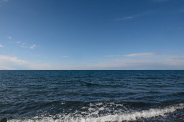 Yumuşak dalgalar sahili okşar, derin mavi okyanusla kusursuz bir şekilde harmanlarlar. Geniş gökyüzü uzanıyor, dinlenmek ve düşünmek için mükemmel sakin bir atmosfer yaratıyor..