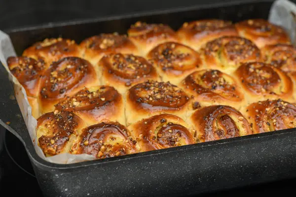 Fırından taze pişmiş tatlı rulo, mükemmel bir şekilde yükselmiş ve altın kahverengidir. Çekici aroması sıcacık mutfağı dolduruyor, herkese güzel bir ziyafet vaat ediyor..