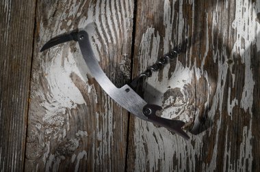 Güneş ışığı, kırsal ahşap üzerinde uzanan ve sıcaklık ve yaratıcılık hissi uyandıran el yapımı bir tirbuşonu ön plana çıkarıyor..