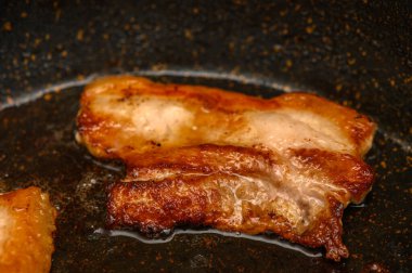 Sulu domuz eti bir tavada kızarıyor, altın-kahverengi bir kabuk elde ederken lezzetli kokular yayıyor..