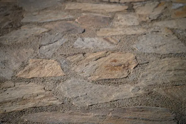 Sert doğal taşlar, batan güneşin yumuşak parıltısıyla aydınlanan sıcak ve davetkar bir yol yaratır..