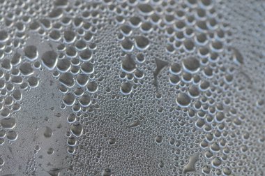 Küçük su damlacıkları cam yüzeyde hassas bir kalıp oluşturur. Etraflarındaki yumuşak ışığı güzel bir şekilde yakalar..