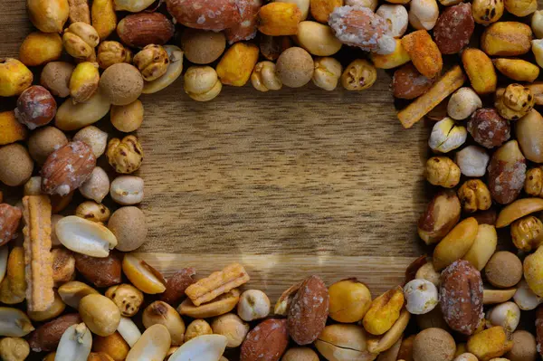 Çeşitli fındık ve abur cuburlardan oluşan canlı bir koleksiyon kırsal ahşap masa üstünde davetkar bir sınır oluşturur..