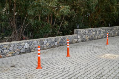 Turuncu trafik konileri, yemyeşil yemyeşil ve taş bir duvarla çevrili sakin bir park alanında açık bir sınır oluşturur..