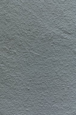 Gri bir duvar yüzeyinin yakın plan görüntüsü eşsiz dokuları ve gölgeleri ortaya çıkararak sanatsal bir ortam yaratıyor..