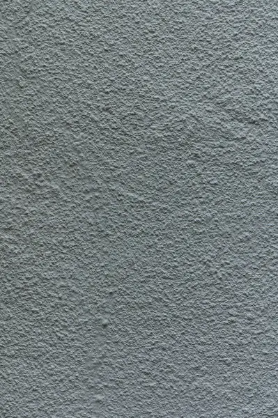 Gri bir duvar yüzeyinin yakın plan görüntüsü eşsiz dokuları ve gölgeleri ortaya çıkararak sanatsal bir ortam yaratıyor..