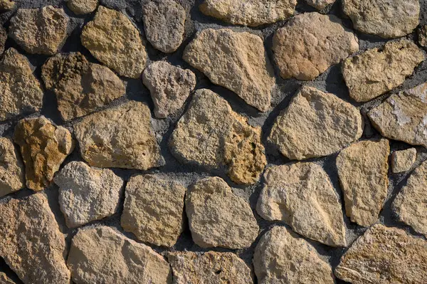 Sıcak tonlu taşlar kırsal bir duvarda mükemmel bir şekilde hizalanır. Gün ortası güneşinin altında parıldar. Doğanın güzelliğini gözler önüne serer..