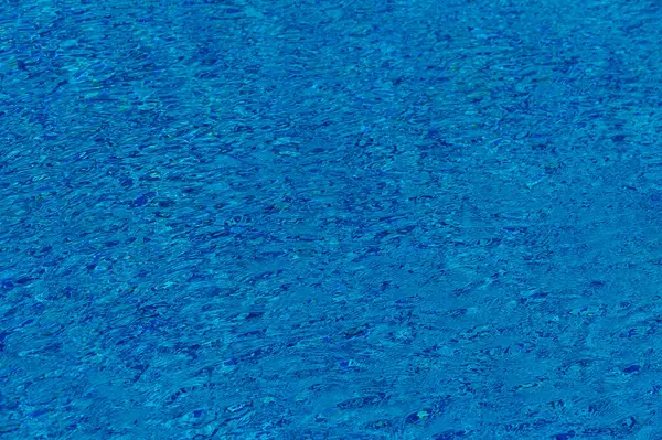 Dalgalanan parlak mavi su dalgaları güneş ışığında parlıyor ve sakin bir yaz atmosferi yaratıyor..