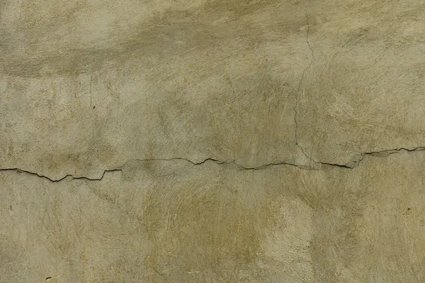 Toprak tonlarının bir karışımı çatlak bir alçı duvarı sergiliyor, dokusunu ortaya çıkarıyor ve zamanla aşınıyor..