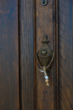 Kaliteli metalden yapılmış çarpıcı bir kapı tokmağı güzel yıpranmış ahşap bir kapıya güzelce asılır. Boncuklar neşe içinde sallanıyor, akşam ışığını yakalıyor..