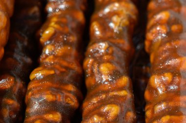 Lezzetli şekerleme, sıcak güneş ışığı altında parıldıyor ve tatlı şurupla kaplanmış karamelize edilmiş fındık karışımı sergiliyor. Yerel bir satıcı, yoldan geçenleri bu eşsiz atıştırmalığa davet ediyor..