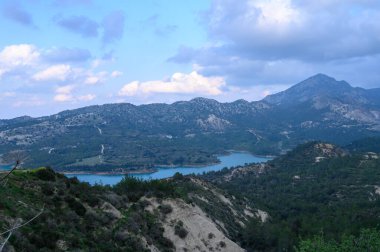 Uçsuz bucaksız yuvarlanan tepeler ufuk boyunca uzanır. Görkemli dağlar tarafından geniş bir gökyüzünün altında taçlandırılır. Vadide sakin bir göl parıldıyor, günün dingin atmosferini yansıtıyor..