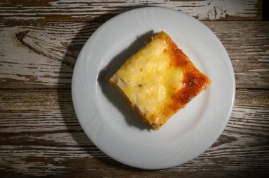 Ev yapımı ev yapımı peynirli lazanyanın nefis bir dilimi beyaz bir tabakta duruyor. Dinleyicileri zengin tabaklarının ve sıcak lezzetlerinin tadını çıkarmaya davet ediyor. Rahatlatıcı bir akşam yemeği için ideal..