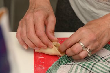 Taze malzemelerin aromasıyla dolu sıcak bir mutfakta, eller ustalıkla katlanmış hamur işi ambalajları, neşe ve lezzet getiren enfes bir mutfak macerasına hazırlanıyor..