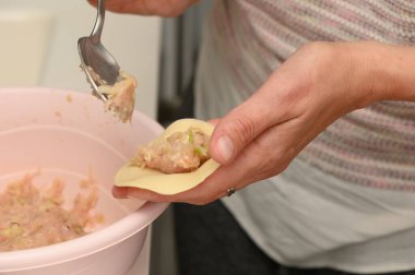 Tuhaf bir mutfakta, yetenekli bir aşçı hamur köftesi paketini lezzetli bir karışım ile dikkatlice doldurur. Yumuşak ışık, dolgu canlandıkça odaklanmış ifadeyi vurgular.