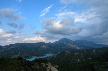 Yumuşak bulutlar ve parlak bir gökyüzü tarafından çerçevelenmiş sakin bir göl üzerinde nefes kesici tepeler kulesi. Doğanın güzelliği gün batımında cezbeder, keşif ve sükuneti davet eder..