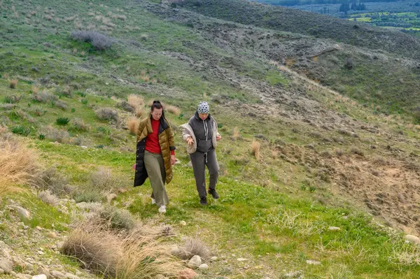 İki arkadaş çimenli bir yamaçta yürürler, temiz havanın ve doğanın güzelliğinin tadını çıkarırlar. Manzara canlı ve yeşil ve yumuşak yamaçlarla dolu..