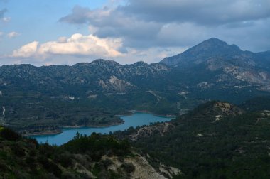 Nefes kesen bir manzara görkemli dağların arasına yerleşmiş sakin bir göl yakalar, alacakaranlık gökyüzünün yumuşak renklerini yansıtır, günün sonunda ve doğanın güzelliğini ima eder..