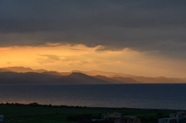 Güneş uzak tepelerin ardında batarken, denizin sakin sularını yansıtan altın renkler gökyüzüne yayıldı. Huzurlu atmosfer huzuru ve tefekküre davet eder..
