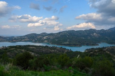 Sakin bir göl öğleden sonra gökyüzünün yumuşak renklerini yansıtır. Yuvarlanan dağlar ve yemyeşil ile çerçevelenir. Doğanın güzelliği bu huzurlu anda duyguları cezbeder..