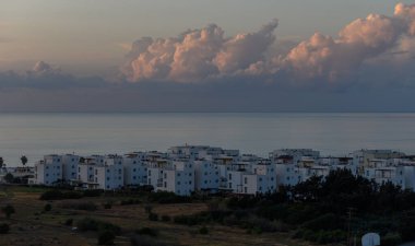 Tüylü bulutlar, güneş batarken kıyı dairelerinin üzerinde tembelce sürüklenerek durgun sulara sıcak renkler döküyor. Bu sakin akşam doğanın ve mimarinin güzelliğini yansıtıyor..