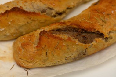 Esnaf ekmeği, kabuklu ve sıcak, parşömen kağıdının üzerinde duruyor. İçi baharat ve otlarla dolu, yumuşak, kokulu bir iç mekan ortaya çıkarıyor..