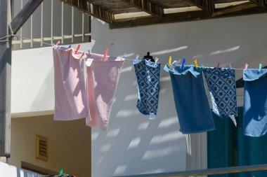 Parlak desenli kumaşlar güneşte kuruyor, çamaşır ipinde beyazlatılmış bir duvara doğru yavaşça sallanıyorlar. Büyüleyici balkon deniz kenarında sakin bir güne işaret ediyor..