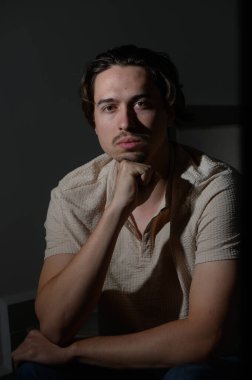 Genç bir adam loş bir odada oturur, dalgın dalgın dalgın dalgın dalgın dalgın dalgın dalgın dalgın dalgın dalgın dalgın dalgın otururken çenesini eline koyar. İfadesi derinlik ve içgözlem aktarıyor, düşünceleri ve duyguları hakkında merak uyandırıyor..