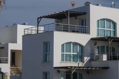 Güzel tasarlanmış bir bina, kıyı ortamında temiz çizgiler ve kalın renkler içerir. Büyük pencereler güneş ışınlarını yansıtıyor, sakin ve davetkar bir atmosfer yaratıyor..