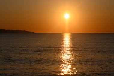 Nefes kesen bir günbatımı okyanus boyunca altın renkler saçar. Güneş ufkun altına batarken gökyüzünü ve suyu aydınlatarak kıyı şeridinde huzurlu bir ortam yaratır..
