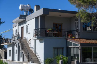 Parlak güneş ışığı, hareketli bir kıyı bölgesinde modern ve şık bir bina yıkar. Sakin bir atmosfer gevşemeyi ima eder, canlı bitkiler açık hava cazibesini arttırır..