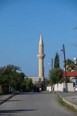 Geleneksel bir minare, yemyeşil tarafından çerçevelenmiş, uzakta dimdik dururken, huzurlu bir yol önümüzde uzanıyor, keşifleri davet ediyor..